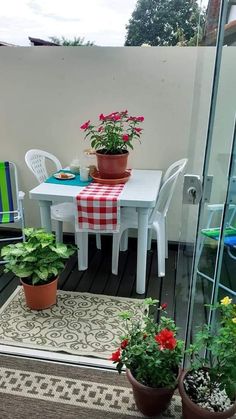 a patio with potted plants on the table and chairs