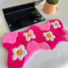 a pink rug with flowers on it next to a laptop