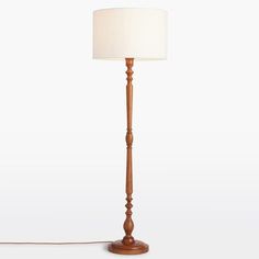 a wooden floor lamp with a white shade on the base and a cord attached to it