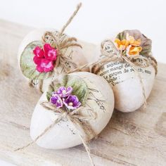 three white pumpkins decorated with flowers on top of a wooden board and twine