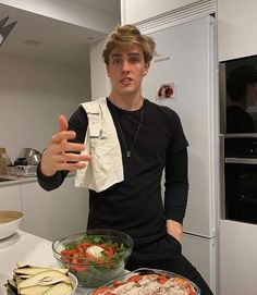 a young man standing in front of a table filled with pizzas and salads