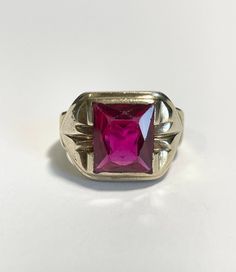 Handsome vintage 10k yellow gold 1940s era ring featuring a vibrant created ruby! The deep red gem weighs an estimated 8.48 carats, is Emerald cut, and bezel set. The substantial setting is detailed with decorative designs on the shoulders. Charming vintage piece of fine jewelry for him or her, featuring July's birthstone!  ERA - Circa 1940s, Retro Era METAL / MATERIAL - 10k yellow gold, 1 created ruby (estimated 8.48 carats) [Synthetic ruby contains essentially the same chemical composition & p Vintage 14k Gold Ruby Ring With Polished Finish, Vintage Ruby Rings With Polished Finish, Antique Ruby Rings With Polished Finish, Classic Ruby Signet Ring, Vintage Yellow Gold Signet Ring With Center Stone, Classic Red 14k Gold Signet Ring, Classic 14k Gold Red Signet Ring, Antique Red 14k Gold Signet Ring, Antique Red Signet Ring In 14k Gold