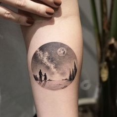 a person with a tattoo on their arm is standing in front of a full moon