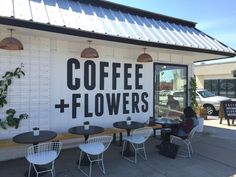 people sitting at tables in front of a coffee and flowers store