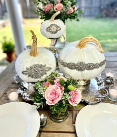 the table is set with white pumpkins and flowers