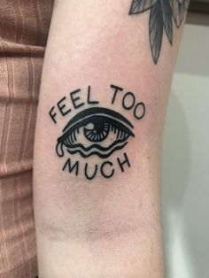 a woman's arm with a tattoo saying, feel too much and an eye on it