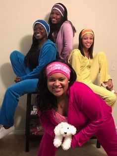 four girls in pajamas and headbands posing for the camera with a teddy bear