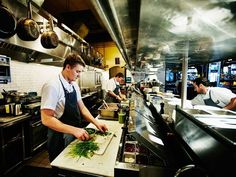 three men in a kitchen preparing food on cutting boards