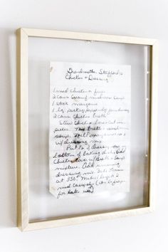 a piece of paper with writing on it in a wooden frame against a white wall