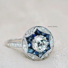 Round Diamond Sapphire Floral Halo Art Deco Ring/Antique Victorian Ring/925 Silver Round Cut Milgrain Vintage Ring/Circa 1920's Style Ring 𝐂𝐞𝐧𝐭𝐞𝐫 𝐒𝐭𝐨𝐧𝐞 𝐃𝐞𝐭𝐚𝐢𝐥𝐬 ↣ Shape : Round Cut ↣ Size : 6mm ↣ Color : DEF White  ↣ Clarity : vvs ↣ Luster : excellent ↣ Make : high quality ✥ 𝐒𝐢𝐝𝐞 𝐒𝐭𝐨𝐧𝐞 𝐃𝐞𝐭𝐚𝐢𝐥𝐬 ↣ Shape : Round Cut  ↣ Color : White & Blue Sapphire ↣ Luster : excellent ↣ Make : high quality ↣ Metal : rose gold - yellow gold -white gold - 925 silver ↣ Making Process : Handmade - crafted by our experienced team ↣ Metal Stamp : yes ✥ 𝐅𝐫𝐞𝐞 𝐄𝐧𝐠𝐫𝐚𝐯𝐢𝐧𝐠 The stones in jewelry are 100% hand-crafted it is cut and polished by our experienced craftsman. Provide you with the best service. -----ENGRAVING IS AVAILABLE ----- > name > birth date > engagement date > White Gold Ruby Ring, Antique Rings Victorian, Edwardian Engagement Ring, Vintage Wedding Jewelry, Trending Engagement Rings, Ring Trends, Art Deco Engagement, Victorian Rings, Sapphire Engagement Ring