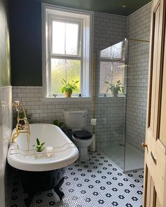 a bathroom with black and white tile flooring and a bathtub next to a window