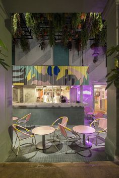 the interior of a restaurant with tables and chairs, plants hanging from the ceiling above