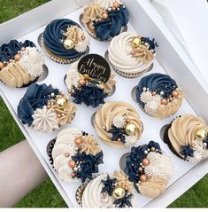 a box filled with blue and white cupcakes on top of a green field