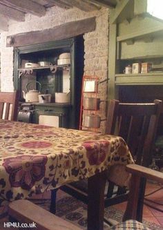 an old fashioned kitchen table and chairs in front of the oven with pots on it