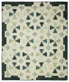 a green and white quilt with trees in the center on it's border,