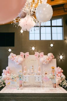 an elaborately decorated stage set up for a baby's first birthday with balloons and decorations