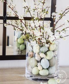 a vase filled with eggs and flowers on top of a table