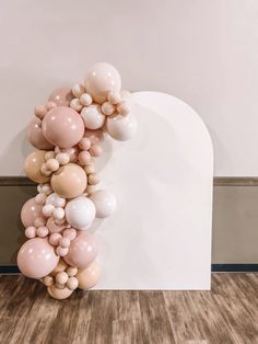 a bunch of balloons floating in the air on top of a white wall next to a wooden floor