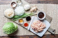 an assortment of food on a cutting board with chopsticks and sauces next to it