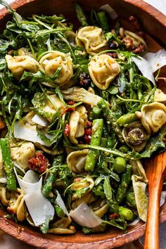 a wooden bowl filled with pasta and veggies