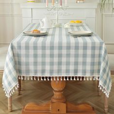 the table is set with two plates on it and candles are lit in the background