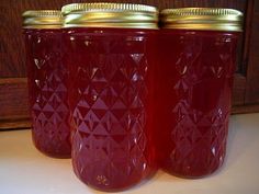 three jars filled with red liquid sitting on top of a counter