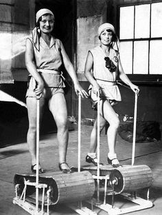 two women in bathing suits standing on skis with poles attached to the back of them