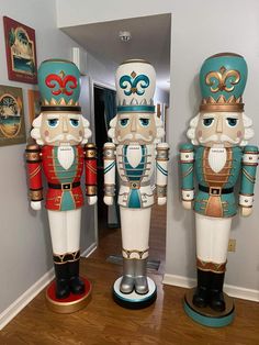 three wooden nutcrackers sitting on top of a hard wood floor next to a doorway