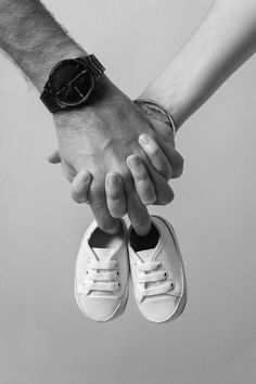 two people holding hands while standing next to each other on top of a pair of white shoes