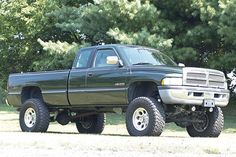 a large black truck parked in front of some trees