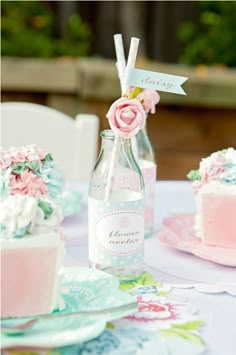 a table topped with two cakes covered in frosting next to a bottle of wine