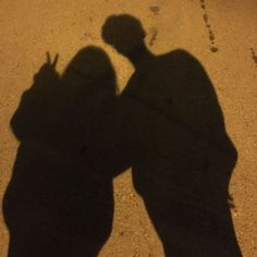 two people standing next to each other with their shadows on the ground in front of them