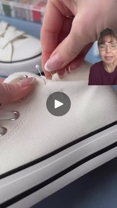 an elderly woman is stitching on a pair of shoes with her thumbnails