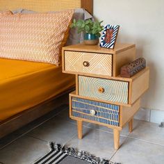 a bed with a yellow comforter next to a wooden night stand on top of a rug