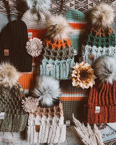 several knitted hats with pom - poms on top of each other and one flower in the middle