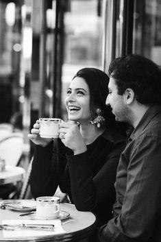 black and white photograph of two people sitting at a table with cups in their hands