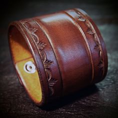 "This brown leather cuff is 2.25\" wide and uses Natural vegetable tanned leather and is hand dyed in a beautiful saddle brown! A classic stamped border and tooled center adorn the main cuff and another tooled section contains hand aged nickel snaps and a beautiful old school, aged copper rivet! I'll need your wrist size for this cuff! Please use the instructions in the pics above! - 2.25' wide - vegetable tanned leather - Old west style Thx! Freddie"