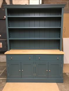 a blue bookcase with drawers and cupboards in the process of being painted to look like wood