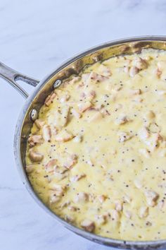 a pan filled with food sitting on top of a white counter next to a knife