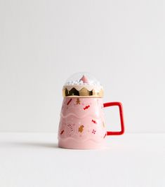 a pink coffee mug with a gold top and handle sitting on a white countertop