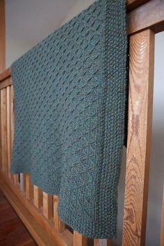 there is a green blanket hanging on the rail in front of a wooden bannister