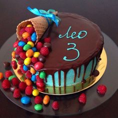 a birthday cake with chocolate frosting and colorful candies on the top, decorated with an ice cream cone