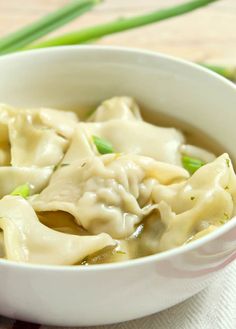 a white bowl filled with dumplings on top of a table