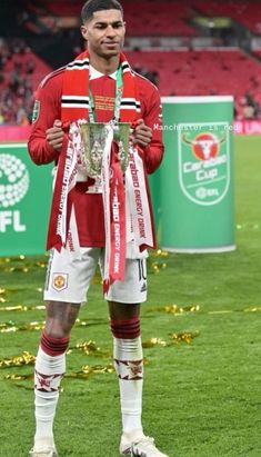 a man standing on top of a soccer field holding a trophy