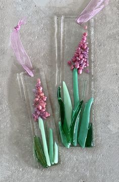 three glass vases with pink flowers and green stems