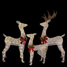 three lighted deers with bows on their antlers are standing next to each other