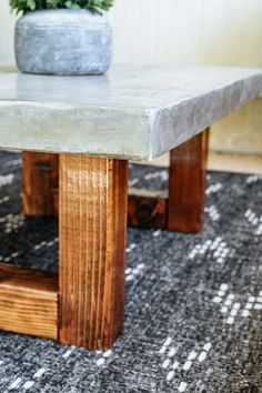 a concrete table with wooden legs and a potted plant on top