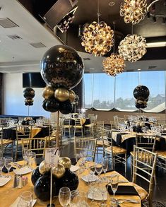 a room filled with lots of tables covered in black and gold balloons