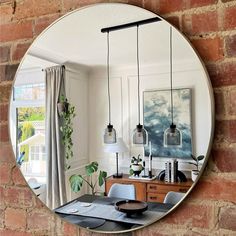 a round mirror hanging on the side of a brick wall above a dining room table