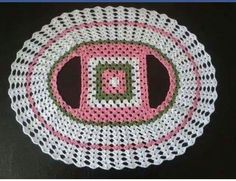 a crocheted doily is shown with pink and green squares in the center